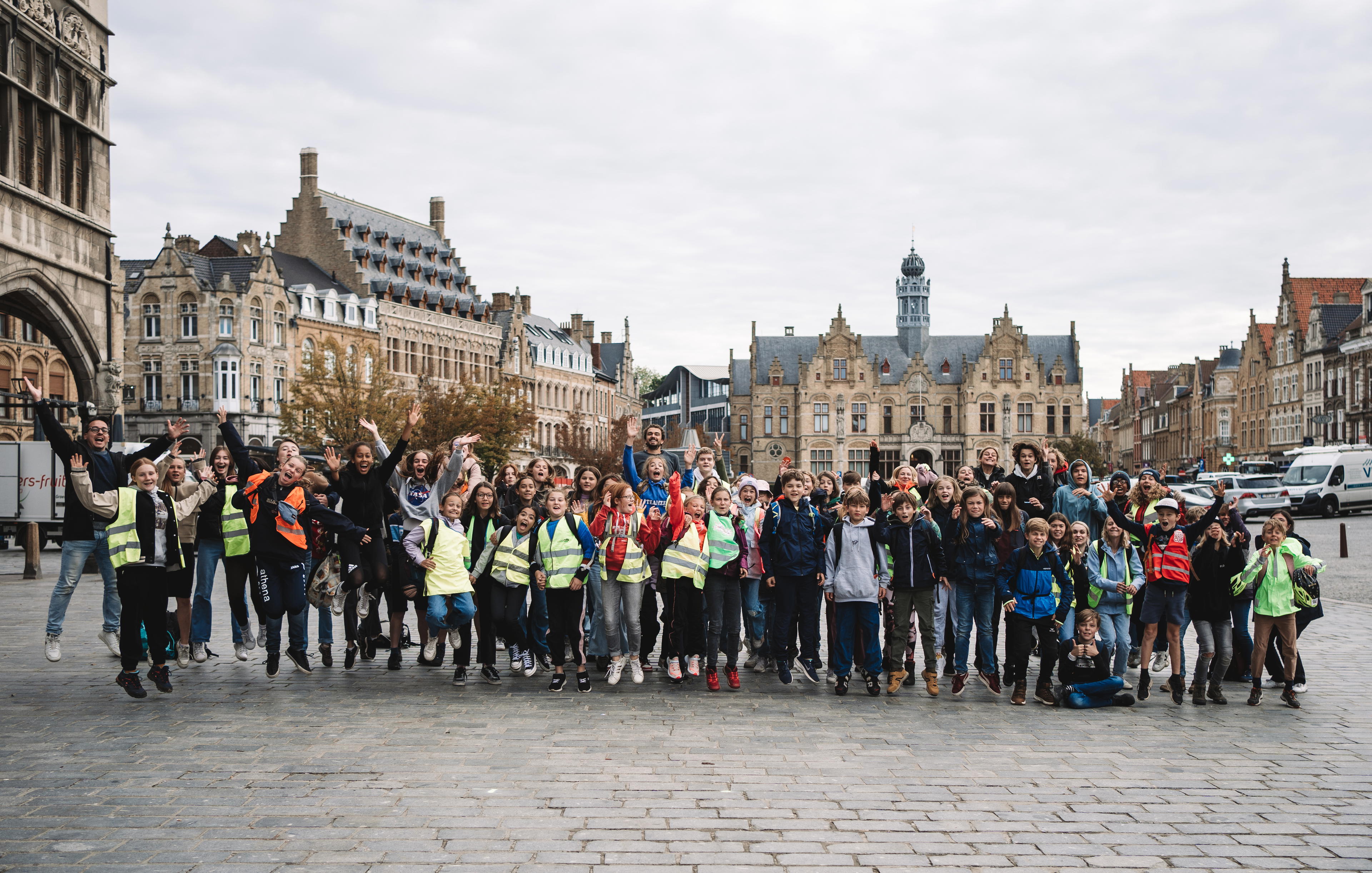 Een grote groep leerlingen uit een lagere school die Urban Hunt in Ieper speelde.